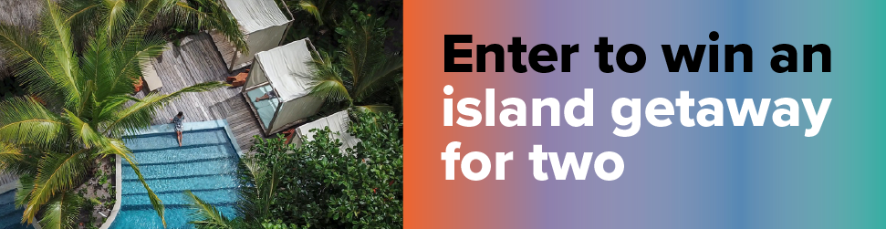 A bird's eye view of a pool in a modern cabin, surrounded by palm trees. Enter to win an island getaway for two.